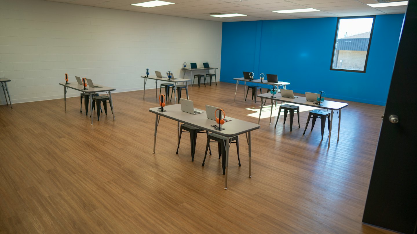 Salle de formation moderne avec ordinateurs portables et casques sur les tables.