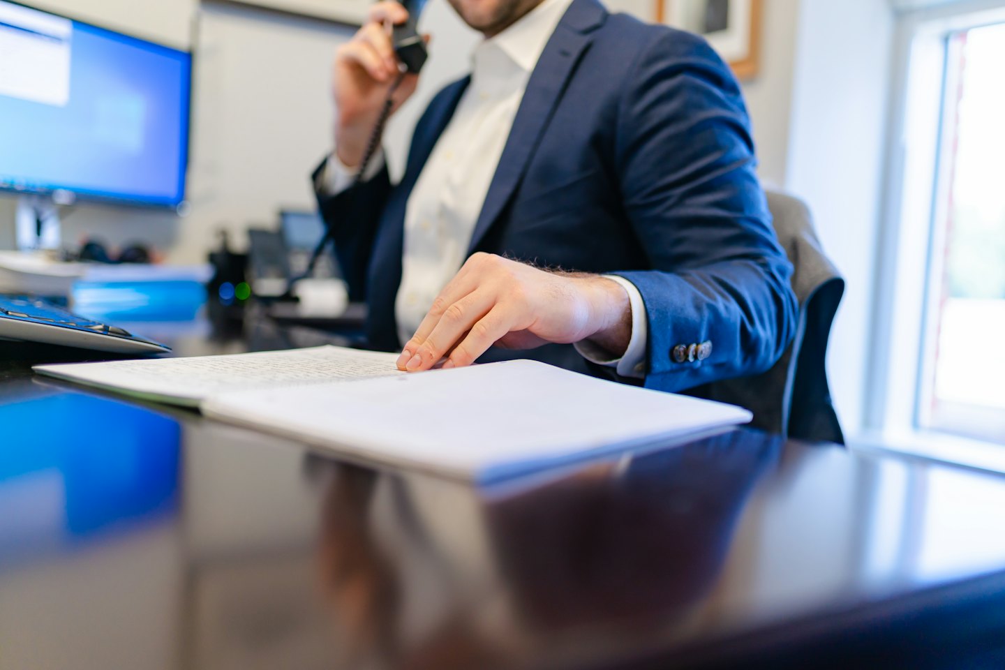 Un homme d'affaires en costume parlant au téléphone fixe à son bureau.