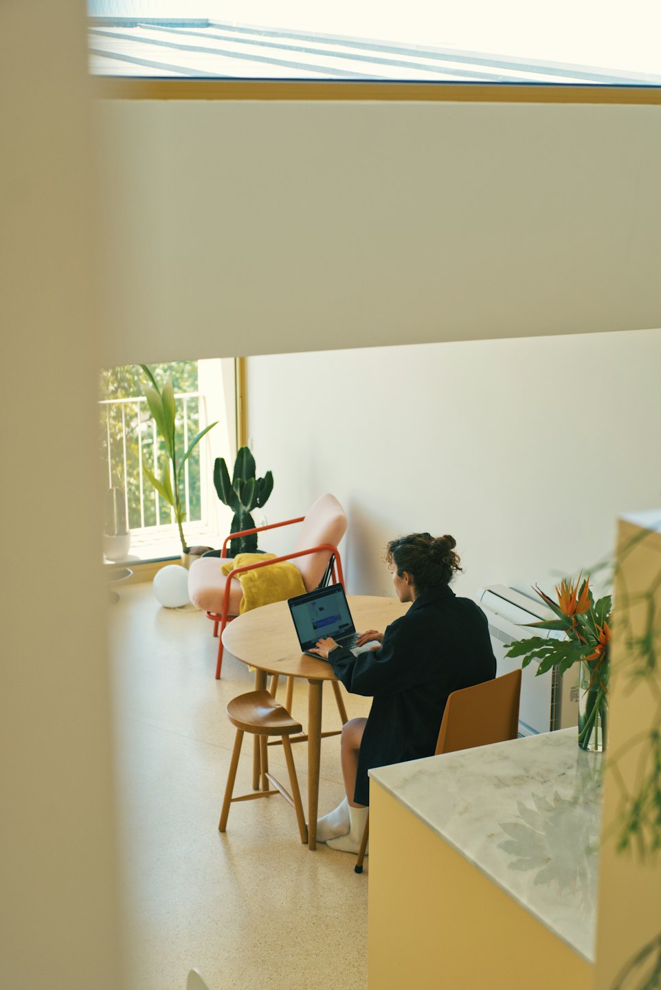 Une personne travaillant sur un ordinateur portable à une table ronde en bois.